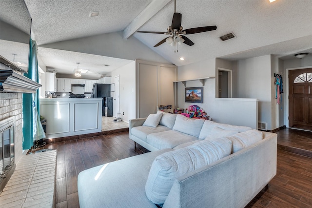 living area featuring lofted ceiling with beams, hardwood / wood-style flooring, a fireplace, and visible vents