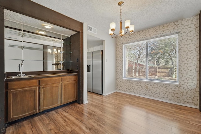 interior space with wallpapered walls, stainless steel fridge, visible vents, and a chandelier