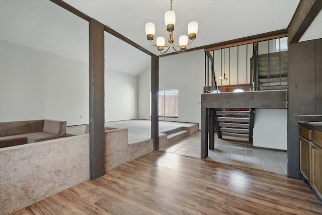 unfurnished dining area with wood finished floors, vaulted ceiling with beams, an inviting chandelier, stairs, and a textured ceiling