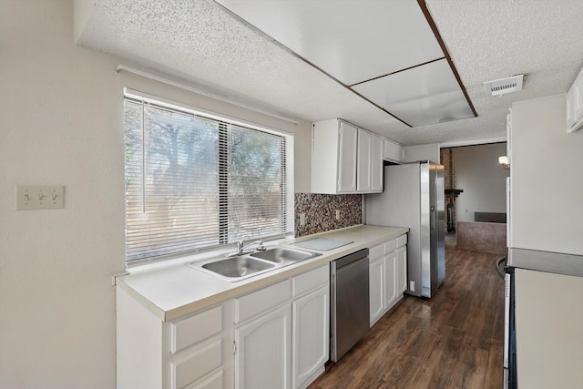 kitchen with appliances with stainless steel finishes, dark wood-style flooring, white cabinets, and a sink