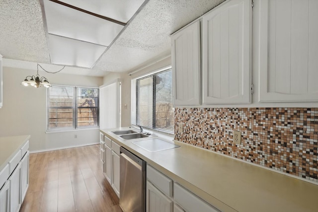 kitchen with a sink, light countertops, stainless steel dishwasher, decorative backsplash, and light wood finished floors