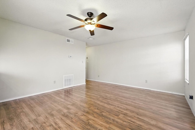 spare room featuring baseboards, visible vents, and wood finished floors