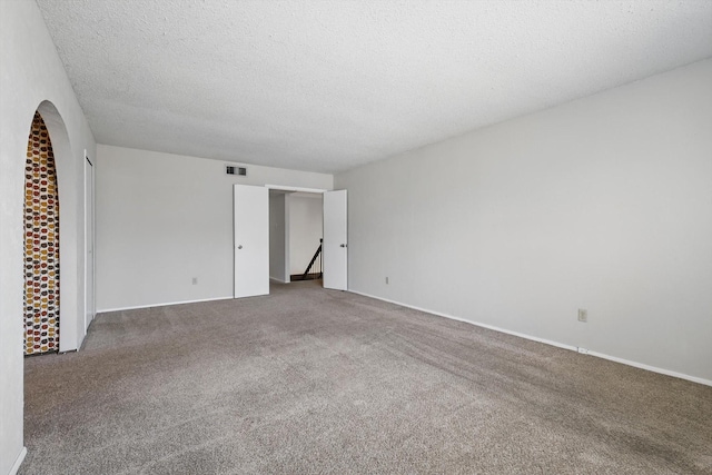 unfurnished room featuring carpet, visible vents, and a textured ceiling