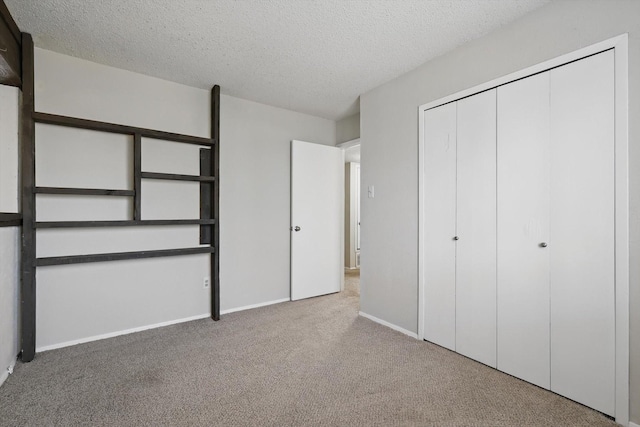 unfurnished bedroom featuring a textured ceiling, a closet, carpet flooring, and baseboards