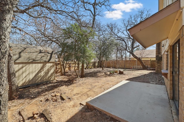 view of yard with a patio area, a fenced backyard, a storage shed, and an outbuilding