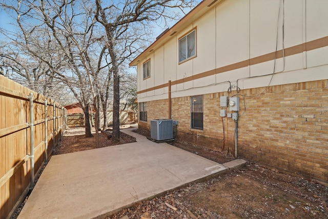 view of home's exterior with a patio, central AC unit, fence, and brick siding