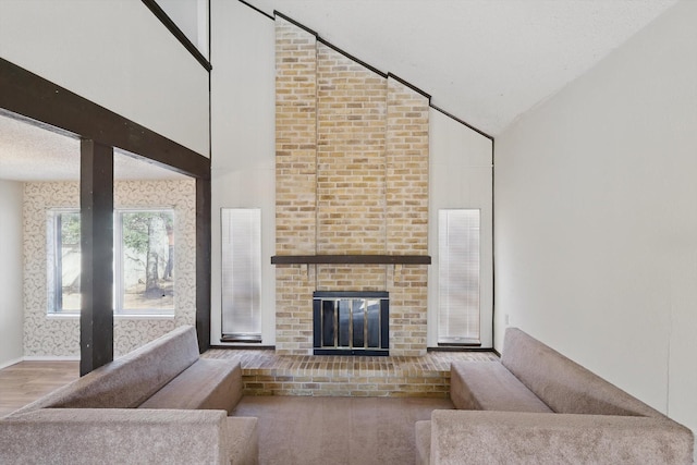 unfurnished living room featuring a fireplace, a textured ceiling, wood finished floors, high vaulted ceiling, and baseboards