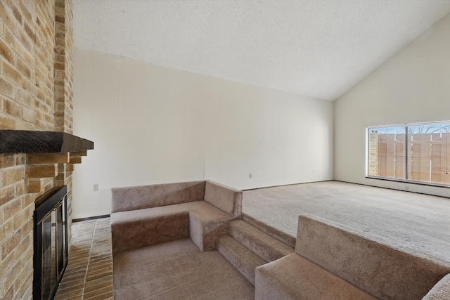 unfurnished living room with a textured ceiling, carpet floors, a fireplace, and high vaulted ceiling