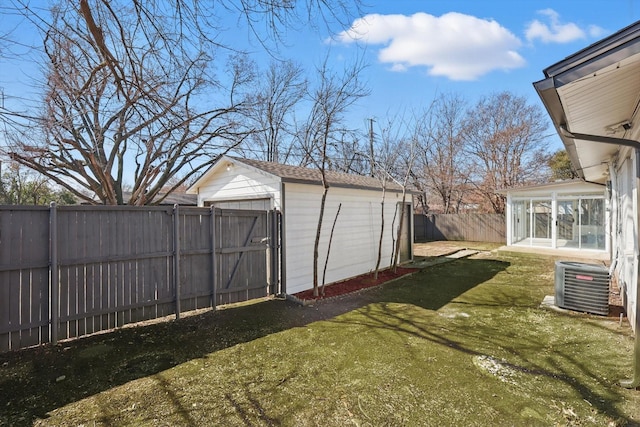 view of yard featuring an outdoor structure, a fenced backyard, a sunroom, and central AC unit