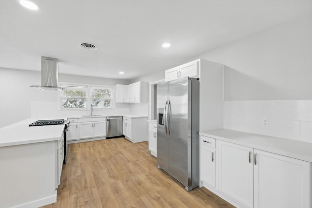 kitchen with white cabinets, visible vents, island exhaust hood, stainless steel appliances, and a sink