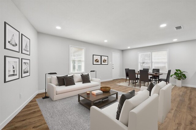 living room featuring baseboards, visible vents, wood finished floors, and recessed lighting