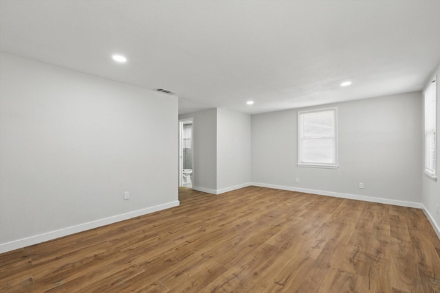 spare room featuring wood finished floors, recessed lighting, baseboards, and visible vents