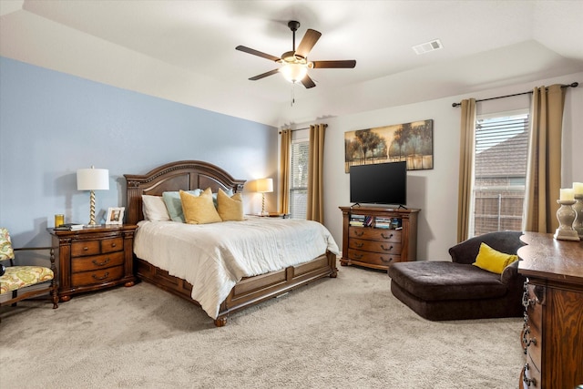 bedroom with lofted ceiling, a raised ceiling, light colored carpet, visible vents, and ceiling fan