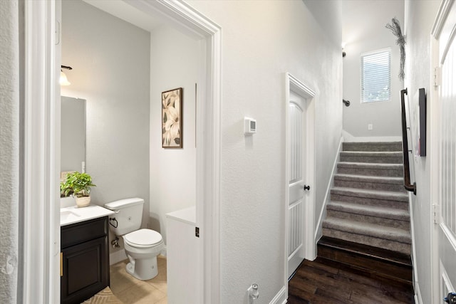 bathroom featuring baseboards, vanity, toilet, and wood finished floors