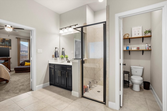 ensuite bathroom featuring toilet, a stall shower, vanity, and baseboards