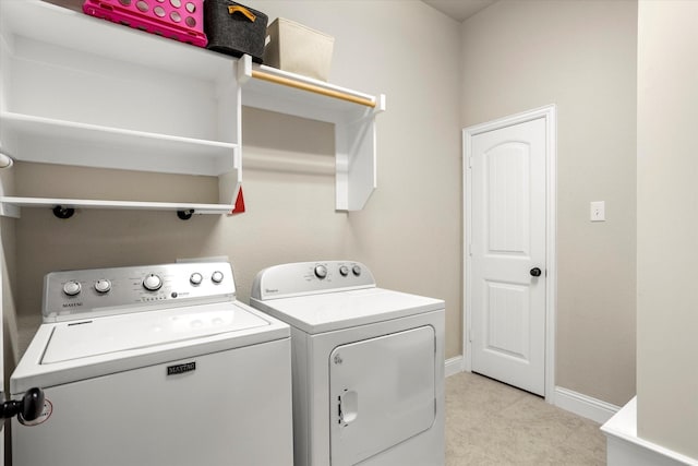 clothes washing area featuring laundry area, baseboards, and washer and dryer