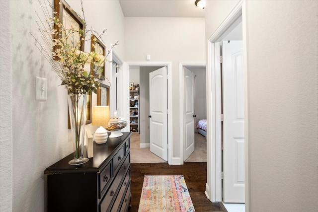 corridor with dark wood-type flooring and baseboards