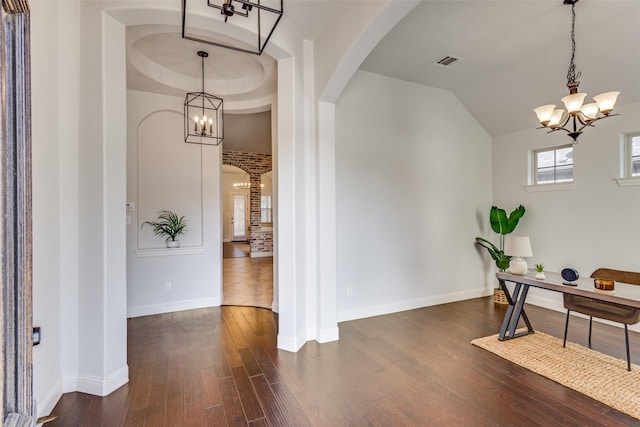 entrance foyer with a chandelier, arched walkways, visible vents, and dark wood finished floors