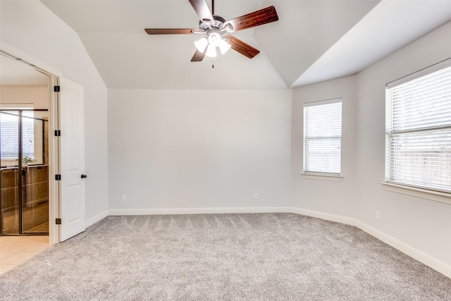 spare room with vaulted ceiling, light carpet, and a ceiling fan