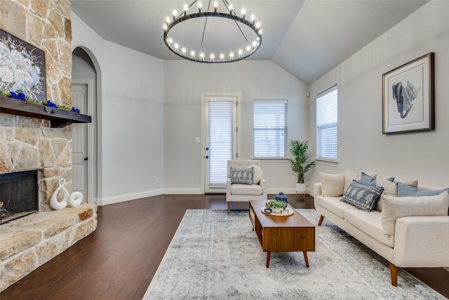 living room featuring a fireplace, wood finished floors, baseboards, vaulted ceiling, and an inviting chandelier