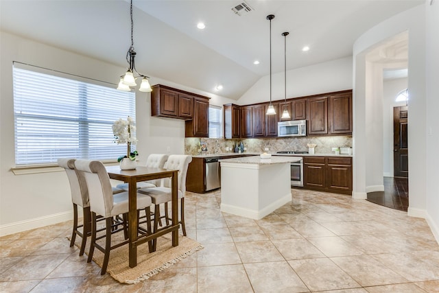 7721 Lake Worth Cv, Mckinney, TX 75071 - kitchen with stainless steel appliances, decorative backsplash, lofted ceiling, dark brown cabinets, and a center island