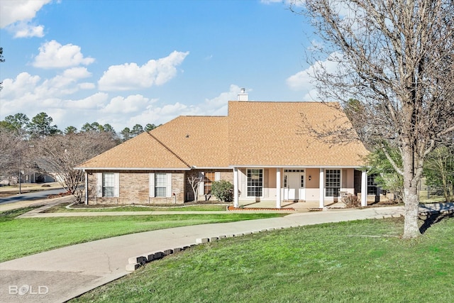 view of front facade with covered porch, a shingled roof, a chimney, and a front lawn