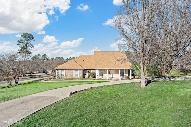 view of front of home with a porch, a front yard, and a chimney