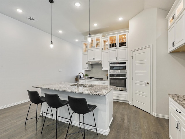 kitchen featuring visible vents, dark wood finished floors, glass insert cabinets, appliances with stainless steel finishes, and a sink