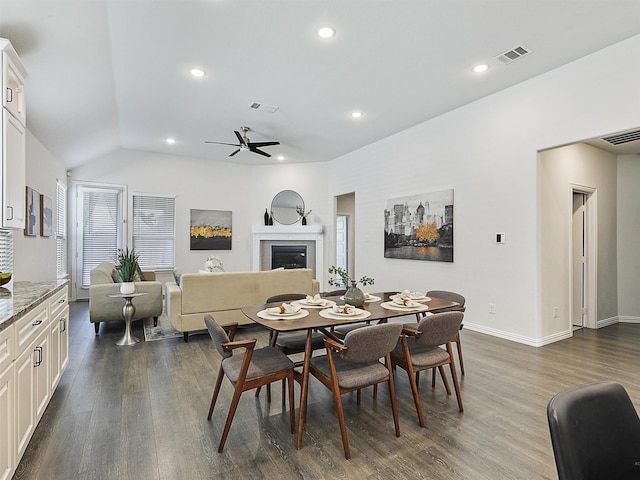 dining room featuring dark wood-type flooring, visible vents, and a tiled fireplace