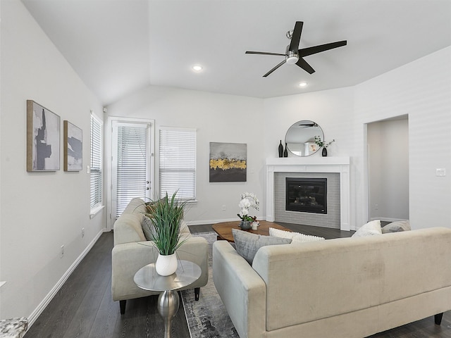 living area with dark wood-style floors, vaulted ceiling, a glass covered fireplace, and baseboards