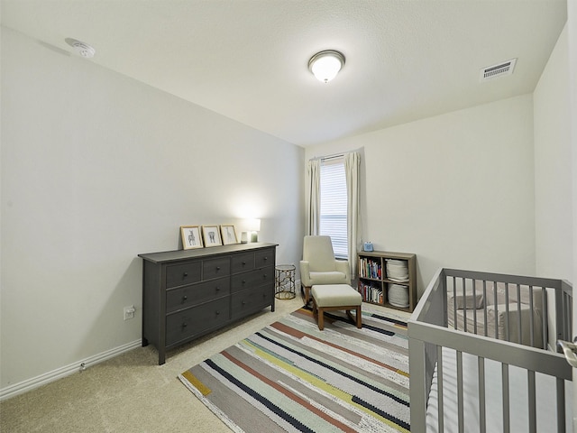 bedroom with a crib, carpet, visible vents, and baseboards