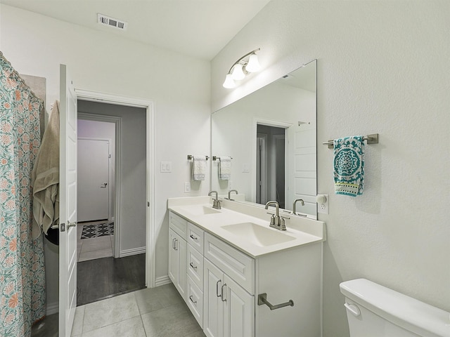 bathroom featuring visible vents, a sink, toilet, and double vanity