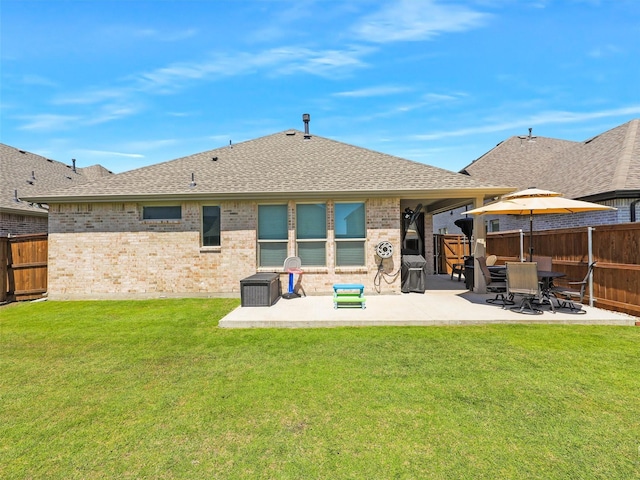 rear view of house with roof with shingles, a patio, brick siding, a lawn, and fence