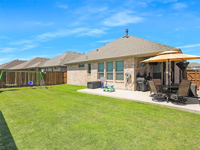 back of property with a shingled roof, a patio, a fenced backyard, a yard, and brick siding