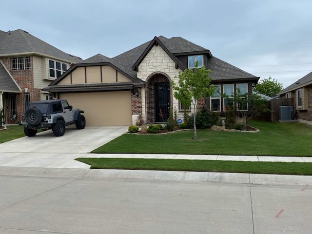 view of front of home featuring a garage, a shingled roof, concrete driveway, central air condition unit, and a front lawn