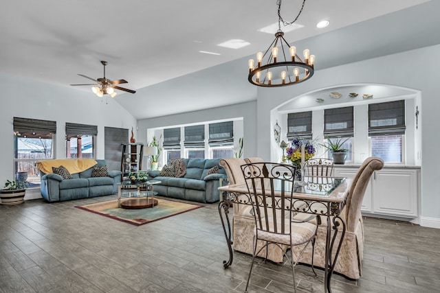 dining space with vaulted ceiling, ceiling fan with notable chandelier, wood finished floors, and baseboards