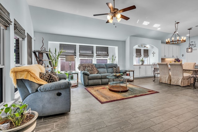 living area with ceiling fan with notable chandelier, arched walkways, and wood finished floors