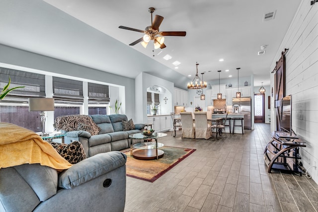 living area with a barn door, recessed lighting, ceiling fan with notable chandelier, wood finished floors, and visible vents