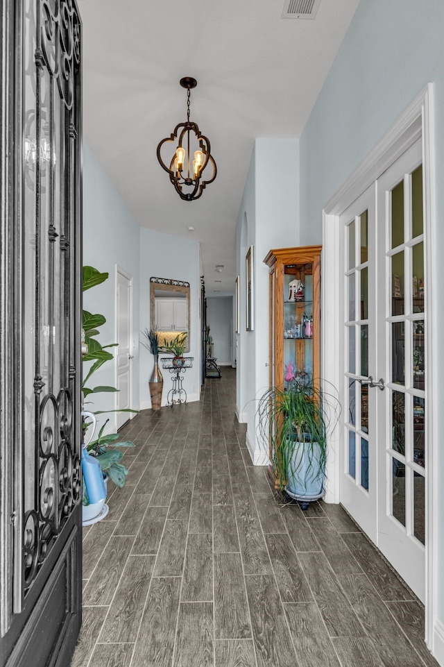 foyer entrance featuring an inviting chandelier, wood tiled floor, visible vents, and french doors