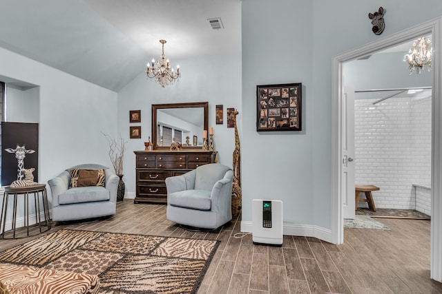 sitting room with lofted ceiling, an inviting chandelier, visible vents, and wood finish floors