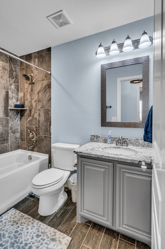 full bathroom featuring visible vents, toilet, wood tiled floor, a textured ceiling, and vanity