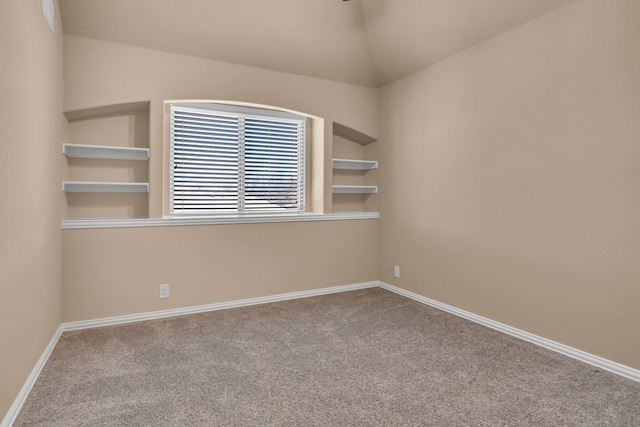 carpeted spare room featuring built in features, lofted ceiling, and baseboards