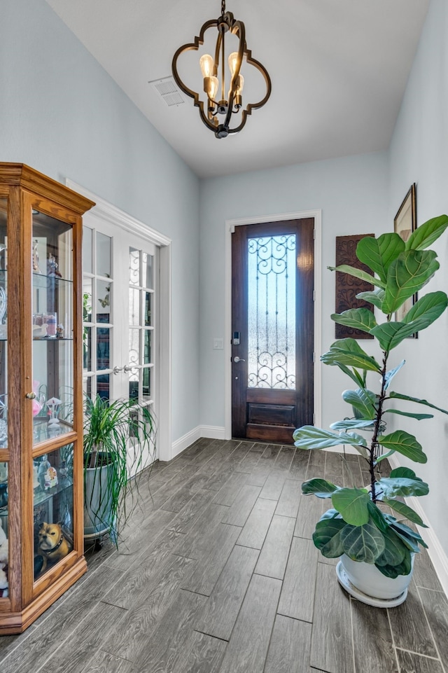 entrance foyer with baseboards, wood finished floors, visible vents, and a notable chandelier