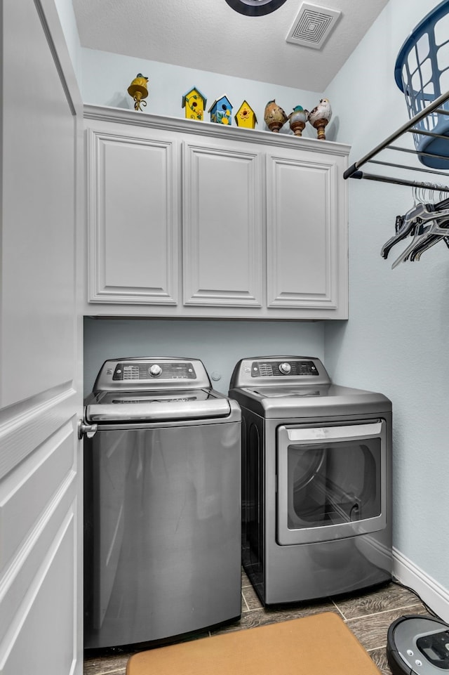 washroom featuring cabinet space, visible vents, baseboards, wood finish floors, and washing machine and dryer