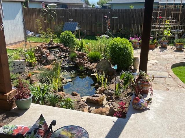 view of yard with fence, a garden pond, and an outbuilding