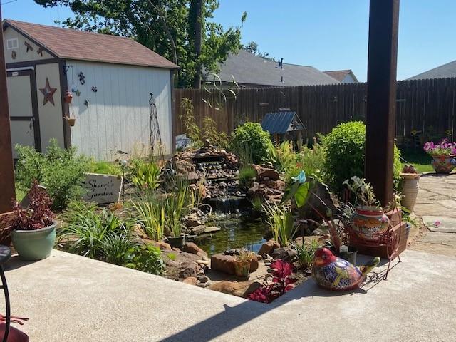 108 Gateway Dr, Alvarado, TX 76009 - view of yard featuring a storage shed, an outbuilding, a small pond, and fence