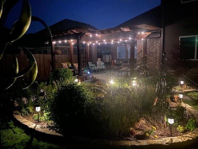 yard at night featuring a patio area, fence, and a pergola