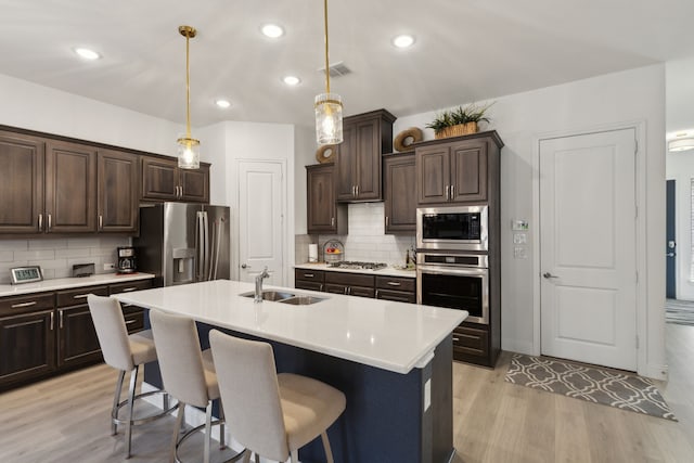 kitchen featuring light countertops, visible vents, appliances with stainless steel finishes, a sink, and dark brown cabinetry