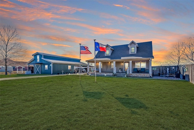 view of front of property featuring covered porch, an outdoor structure, a barn, fence, and a front yard