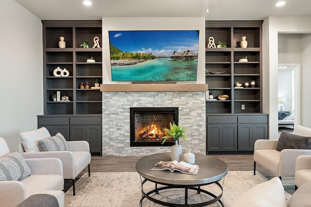 living room featuring recessed lighting, wood finished floors, and a stone fireplace